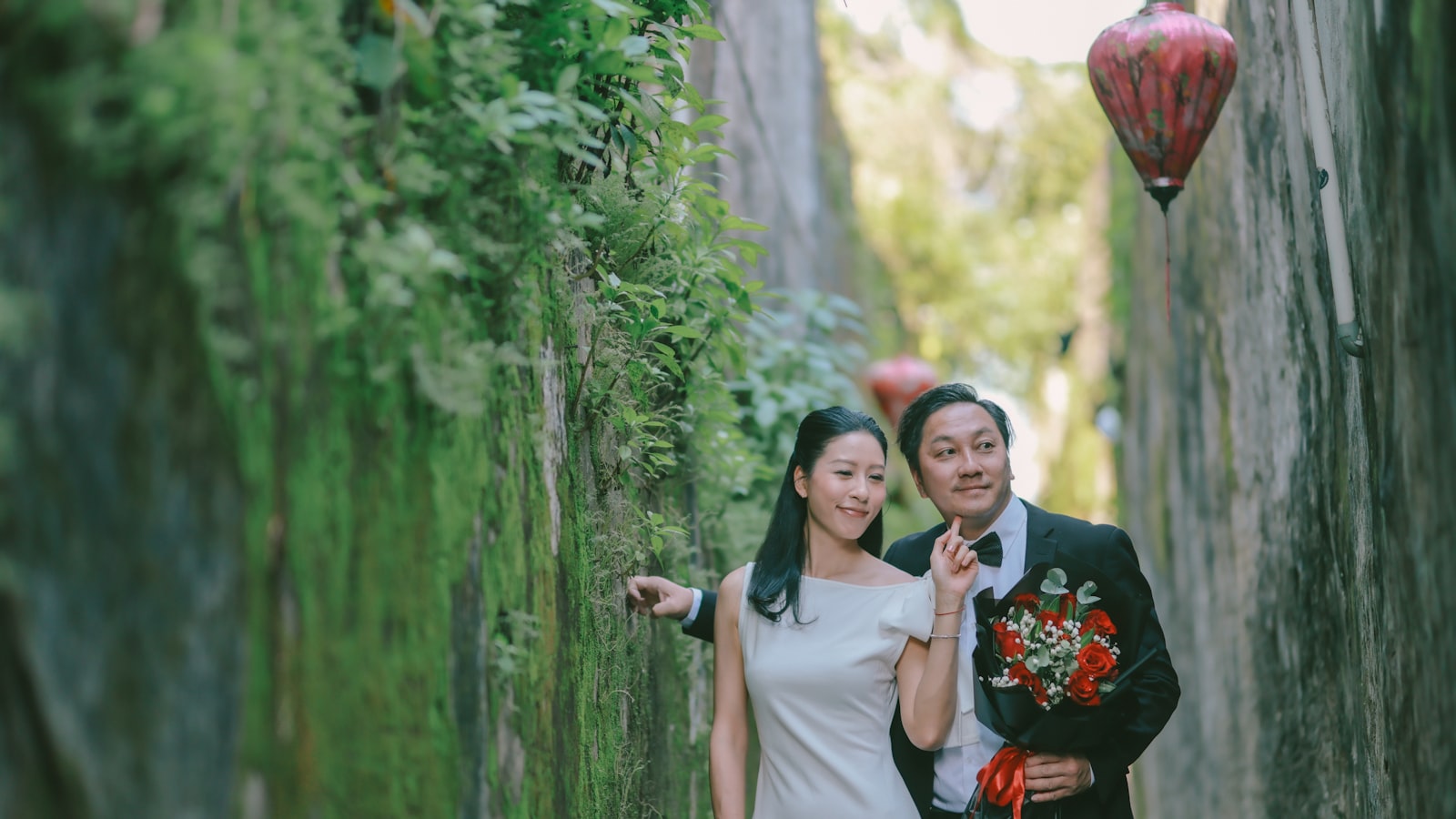 Couple walking in a mossy alley with a lantern