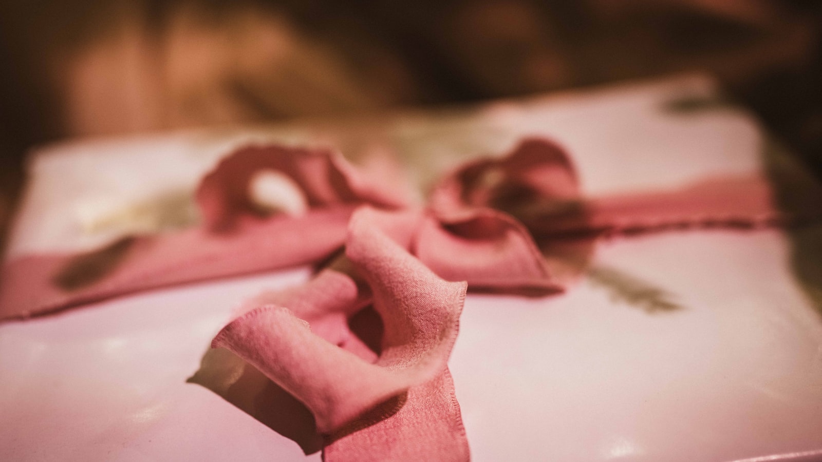 A white gift box with a pink ribbon bow