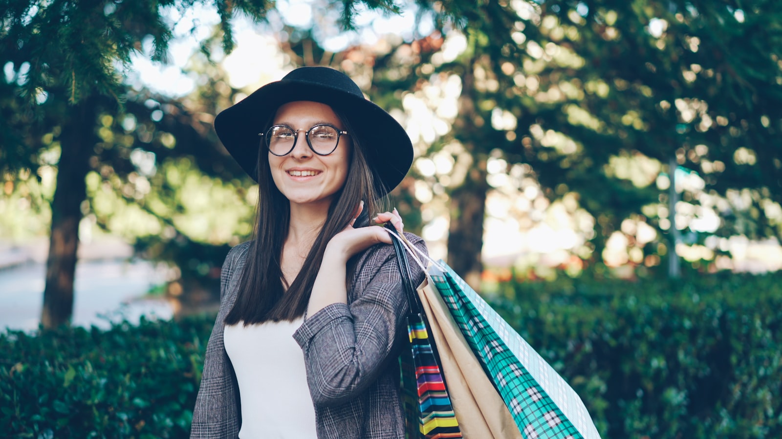 Young woman with shopping bags and hat smiling