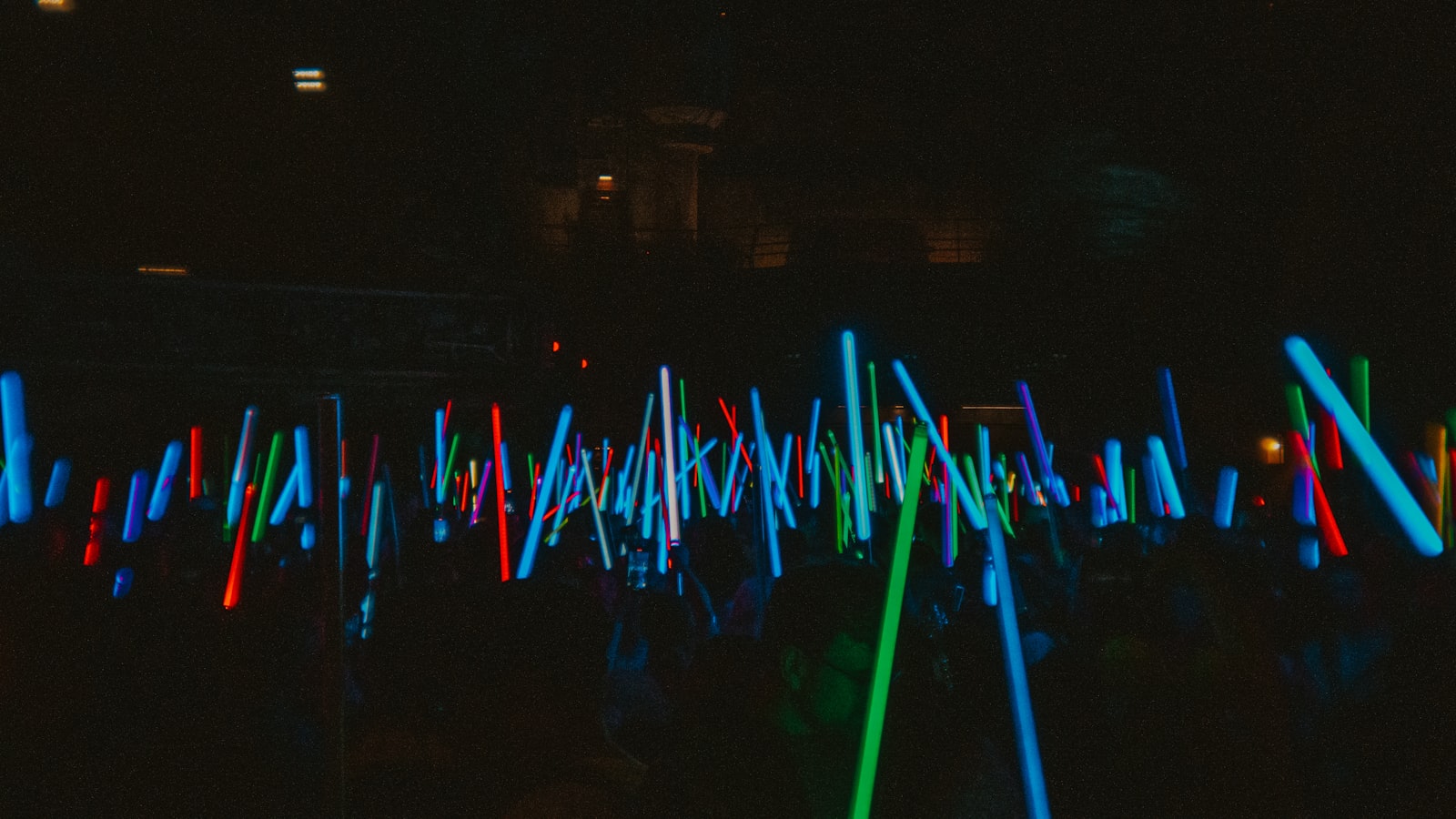 Many glowing light sticks fill the dark space.