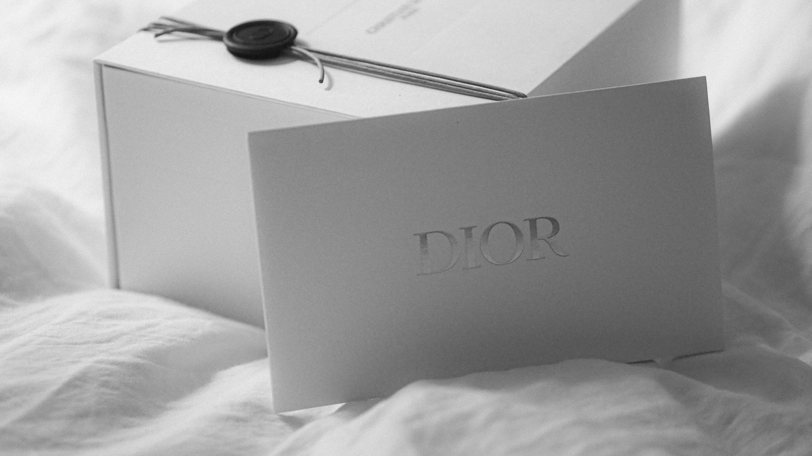 Dior gift box with a card on white fabric