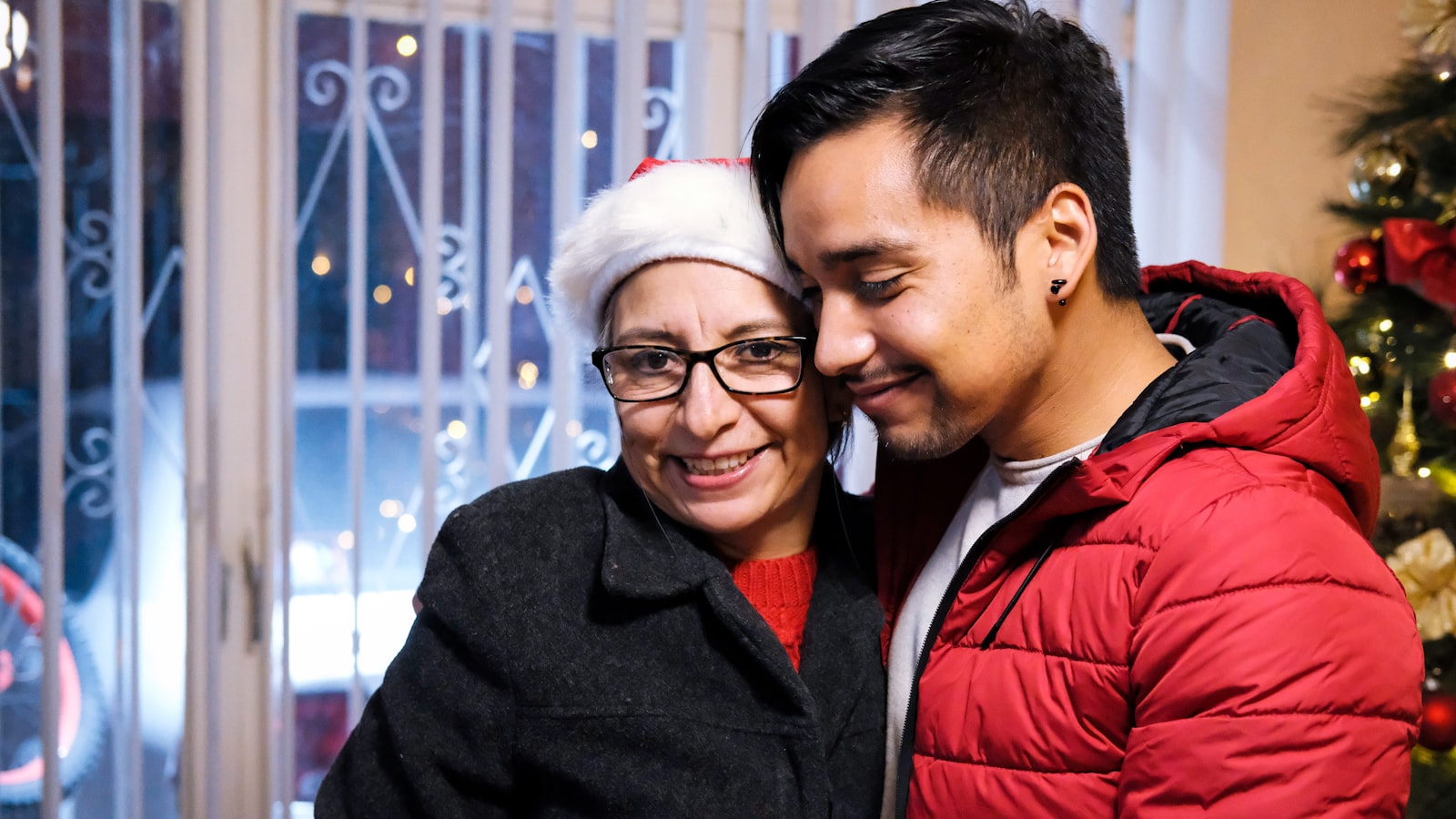 a man and woman standing next to a christmas tree