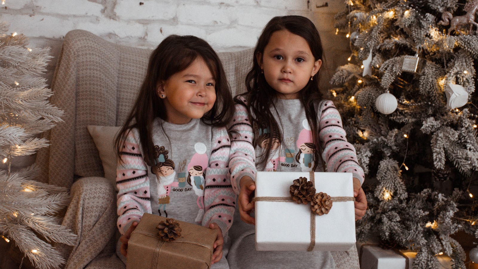 two little girls sitting on a couch with presents
