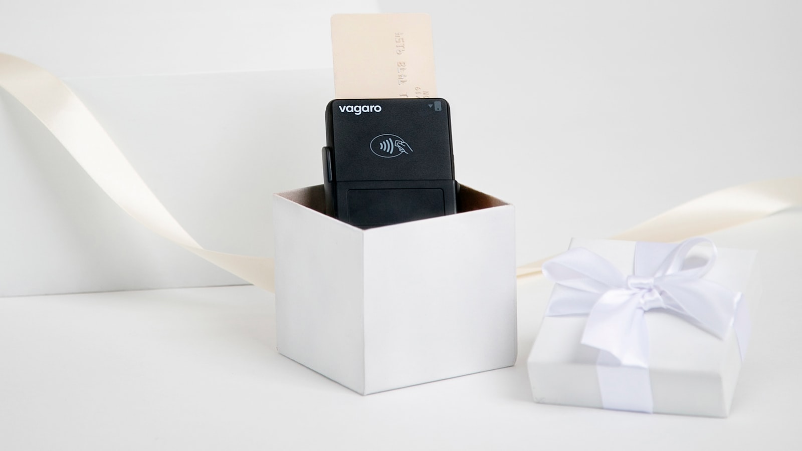 Black device in a white gift box with ribbon