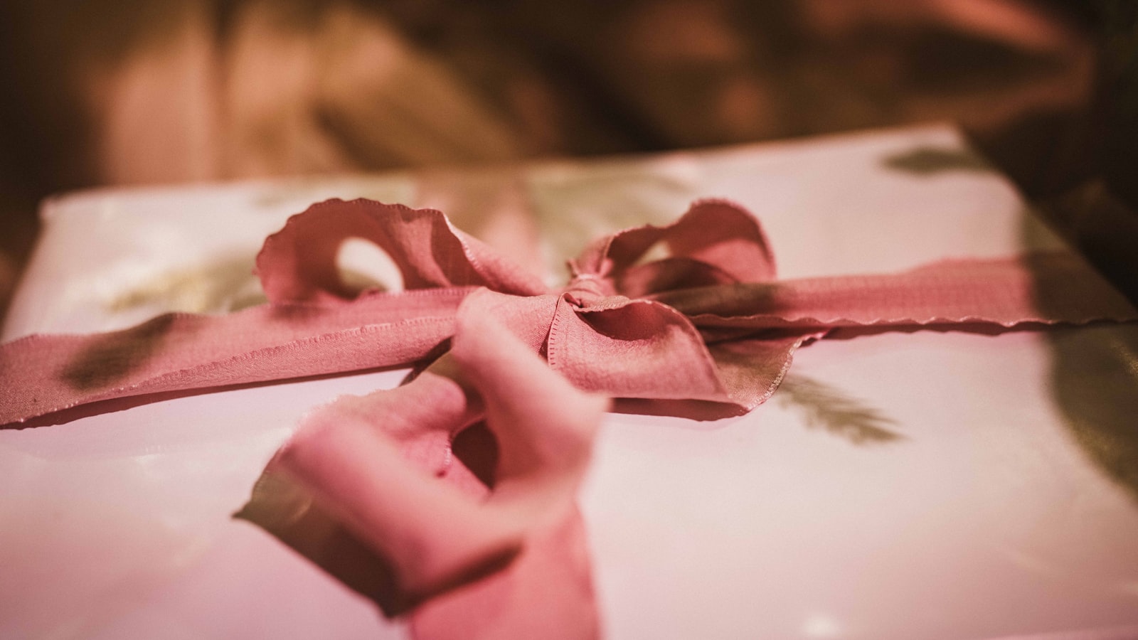 A hand tying a ribbon on a gift box