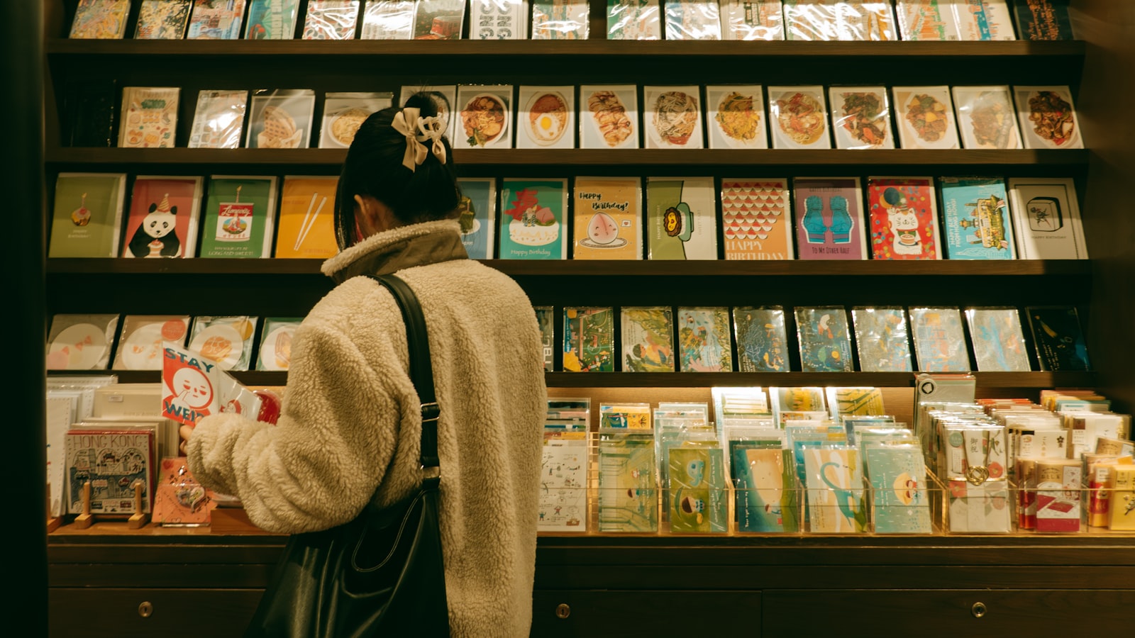 A woman browses postcards in a gift shop.